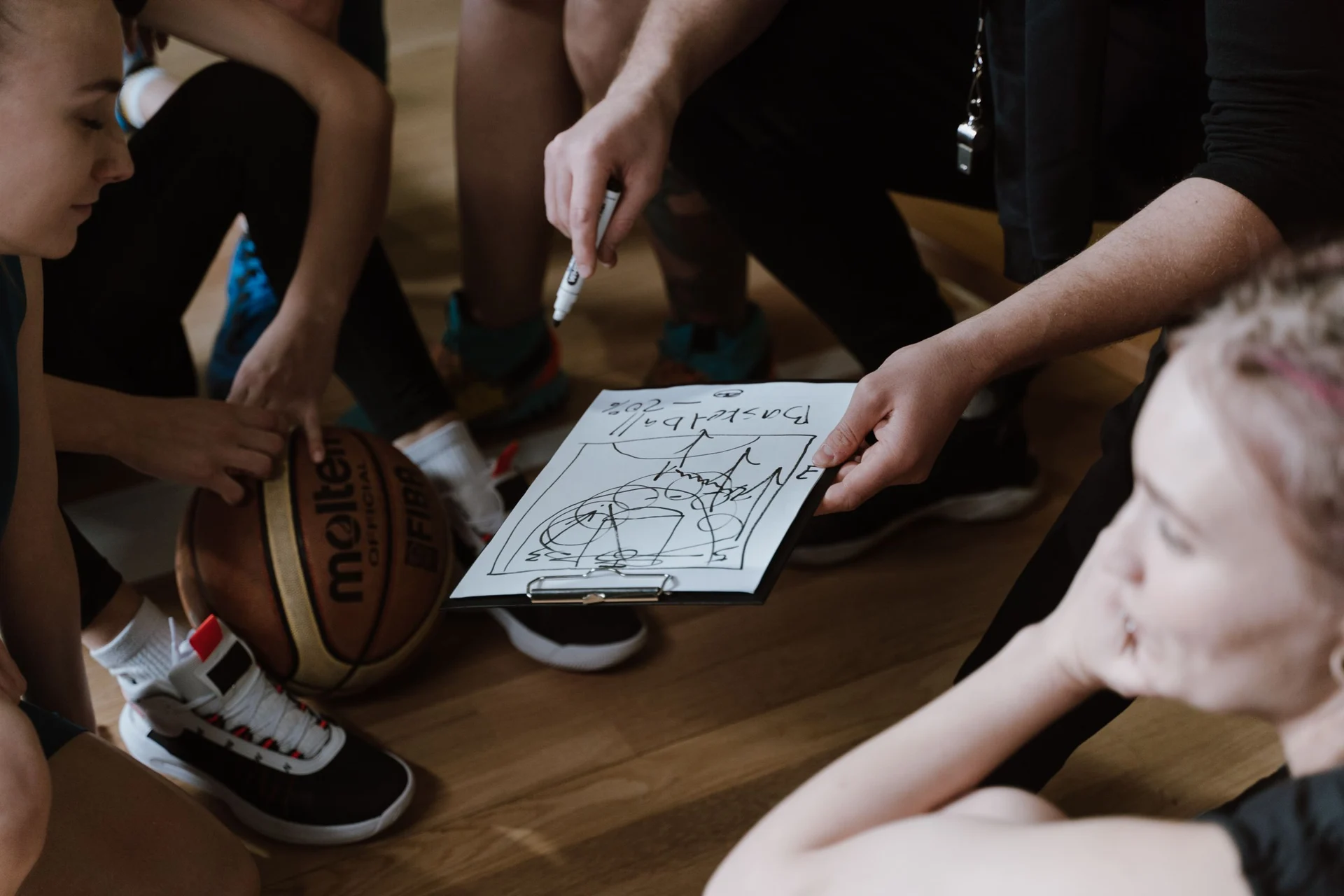 A coach and basketball players discussing a play together